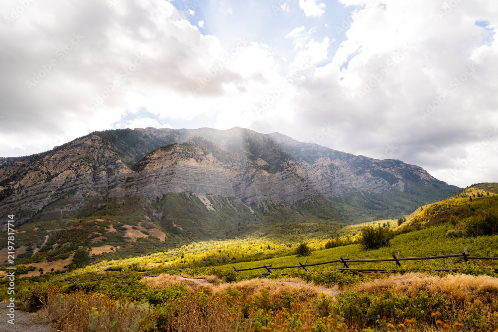 Obraz premium Sunlight Over Autumn Foliage and Rugged Wasatch Mountains Near Kyhv Peak Provo Utah