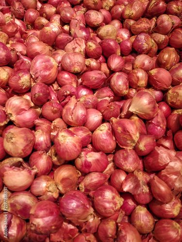 Fresh red onions. Fresh red shallots stacked together in a market background