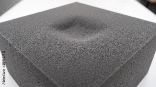 Dark grey foam block with rectangular indentation for industrial testing and material study.