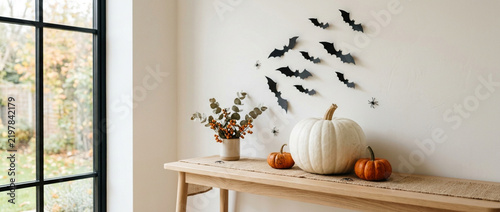 Halloween decor: pumpkins, bats on wall and autumnal foliage on table