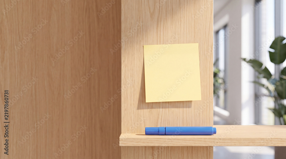 Obraz premium Blank yellow sticky note attached to a light wooden wall with a blue marker on a shelf in a bright modern minimalist office interior, perfect for business reminders, to-do lists, and tasks.