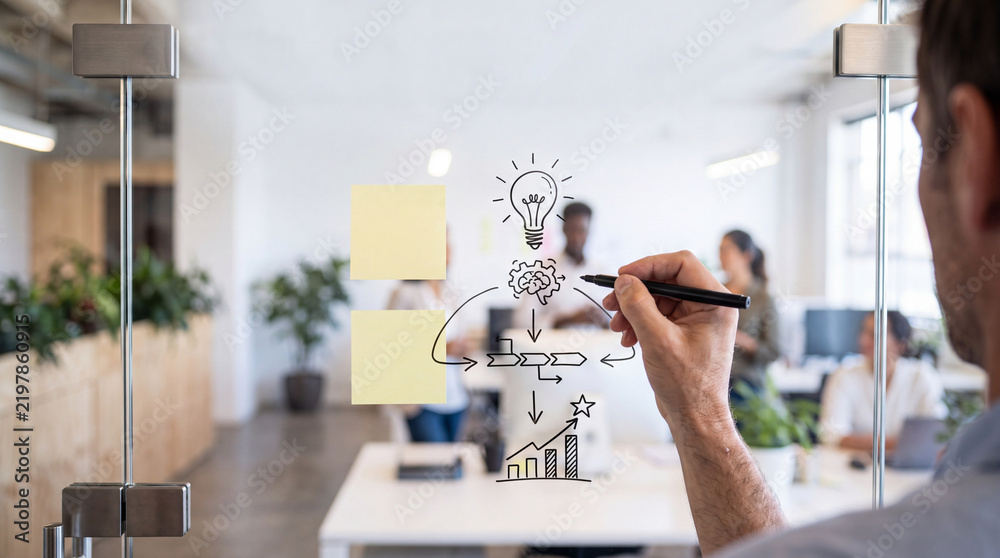 Fototapeta premium Close up of Businessman Hand Drawing Creative Business Strategy Flowchart and Innovation Idea Icons on Glass Wall in Modern Office with Diverse Team in Blurry Background for Startup Concept
