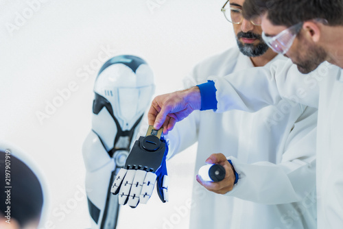 Картината върху платно Collaborative robotics testing: a researcher fingertip meets the black mechanica