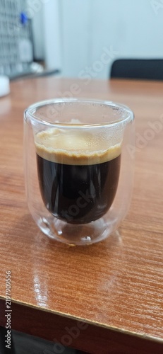 Fresh espresso with thick crema in double wall glass cup on wooden table