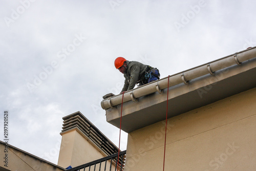Professional industrial climber repairing building rain gutter system