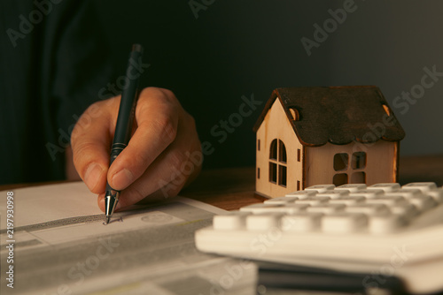 Obraz na plátně Close up of house model, calculator and pen on wooden table.