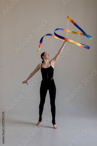 Quadro su tela Young rhythmic gymnast girl performing routine with colorful ribbon in studio