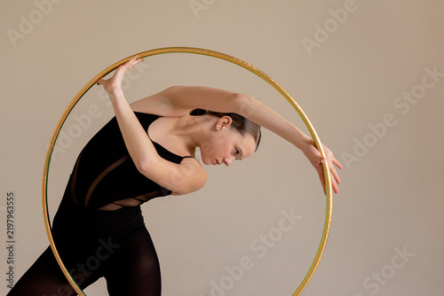 Quadro su tela Graceful girl gymnast posing framed by rhythmic gymnastics hoop against plain ba