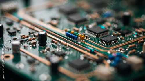 Close up of a green electronic circuit board with integrated circuits, resistors, and copper traces visible in a tech hardware device