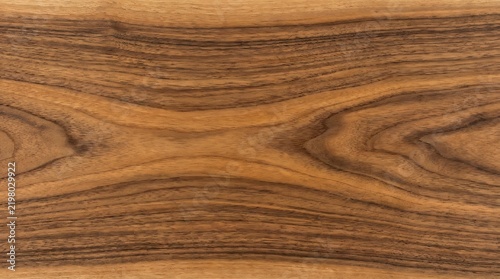 Detailed horizontal walnut wood grain texture featuring rich warm brown tones with elegant dark swirls and natural organic patterns for sophisticated interior design background surfaces