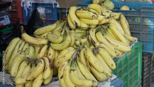 Fresh ripe yellow bananas stacked in bunches on market stall display