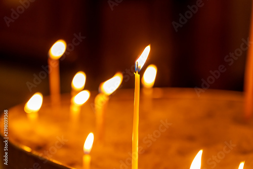 Fotografie Close-up of flickering candle flames casting a warm glow in a dimly lit space
