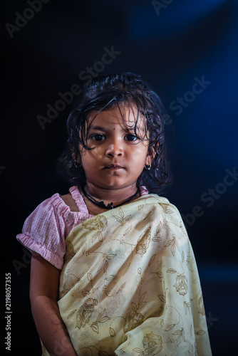 Quadro su tela Little Indian girl standing poised in traditional saree against blue background