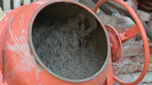 Concrete mixer blending mortar on a construction site. Rotation of an orange concrete mixer drum with mortar inside, symbolizing the construction process and material production