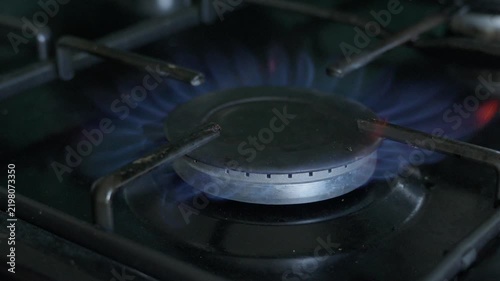 Close-up of blue gas flames burning on a stovetop burner. Slow motion
