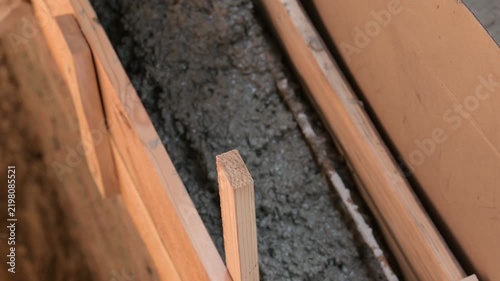 Pouring concrete mortar into wooden foundation formwork. Close-up of fresh cement mixture inside formwork, symbolizing the foundation construction process and creating a strong base