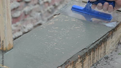 Smoothing fresh concrete foundation with a float. Close-up of a hand with a construction float smoothing poured cement mortar in formwork, symbolizing quality and stage completion
