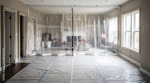 Interior of a house undergoing renovation with a professional dust barrier plastic wall and floor protection covers to prevent mess and debris during home improvement and remodeling works.