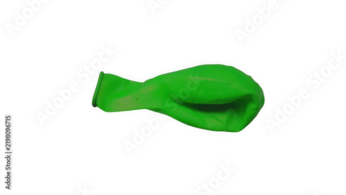 Obraz na plátne A single deflated bright green rubber balloon isolated on a black background, re