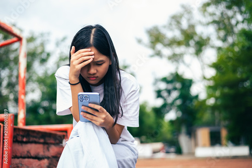 anxious worried teen girl with her smartphone as a conceptual backdrop for cyberbullying social media trauma, teenager mental health crisis, depression and panic attack