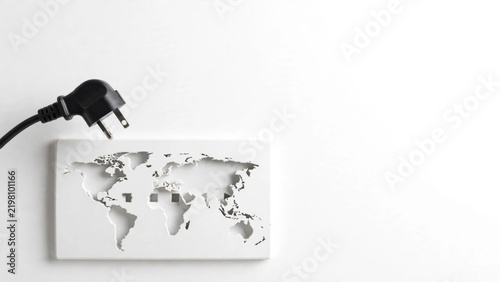Black power plug near white world map cutout on white background