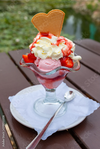 Delicious ice cream sundae served in a clear glass bowl at a outdoor cafe in the afternoon
