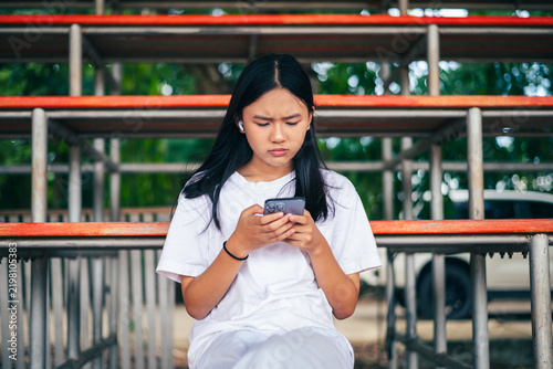 anxious worried teen girl with her smartphone as a conceptual backdrop for cyberbullying social media trauma, teenager mental health crisis, depression and panic attack