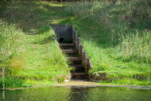 Fotografie Stone Archimedes Screw Water Pump in a Grassy Field