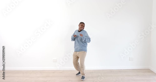 Young boy dancing joyfully in casual outfit against white wall indoors