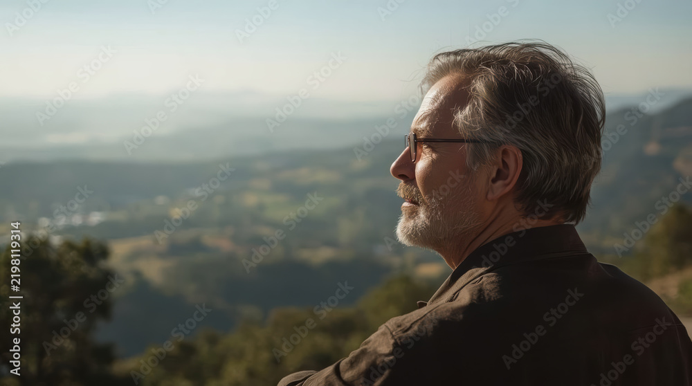 Obraz premium Mature man viewing mountain valley landscape with reflective expression