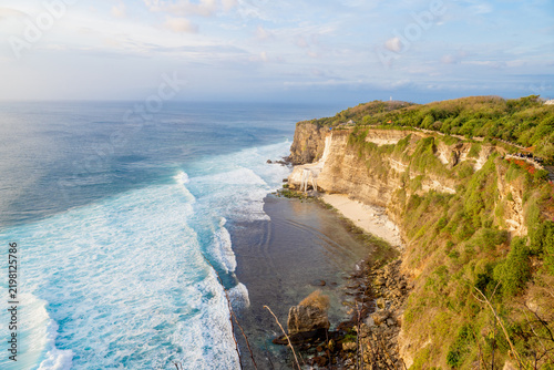 фотографія Dramatic ocean cliff with crushing white waves and hidden beach under evening light in Uluwatu, Bali island, Indonesia