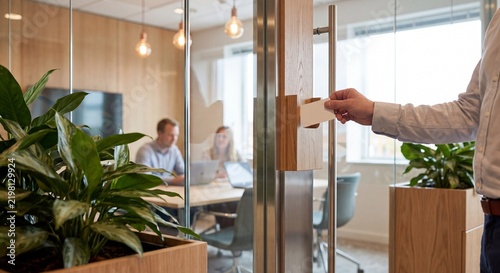 workplace coordinator places room booking card beside planted meeting room to organize shared office space, support team collaboration, and manage daily occupancy
