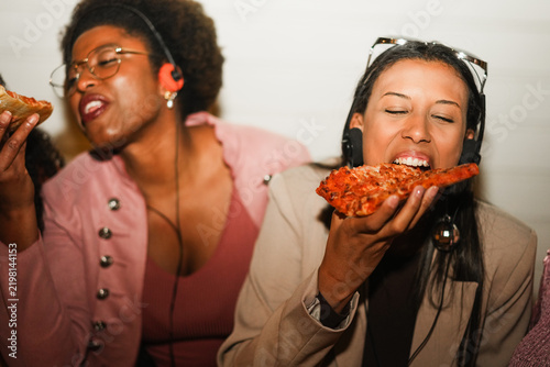 African american girls eating pizza outdoor in the streets after party concert - Food, people lifestyle and nightlife concept - Main focus on right young woman face - UGC flash content