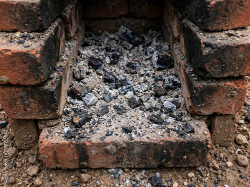 Burnt Charcoal Ashes and Embers Inside a Rustic Outdoor Brick Fireplace Oven After Fire
