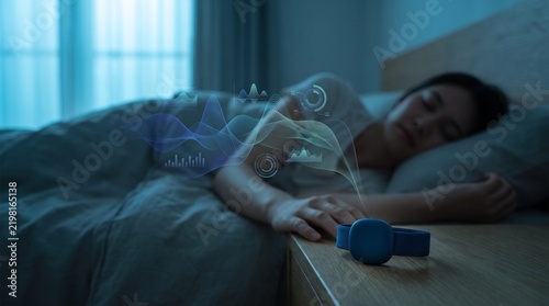 Young woman sleeping in bed while wearing a smart sleep tracking device at night.