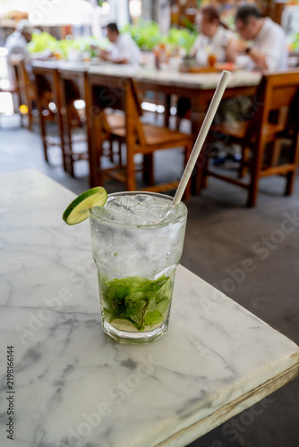 Refreshing iced lime mint soda drink on a marble table in an outdoor cafe.
