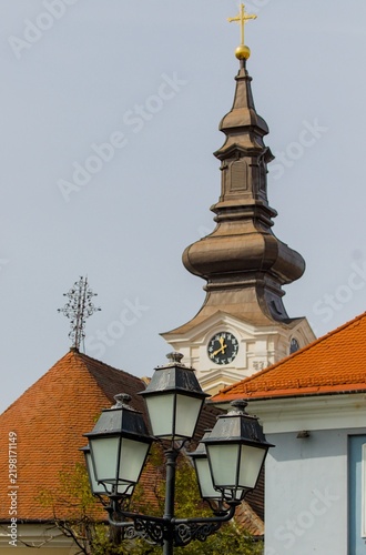 An ornate clock tower rises above old rooftops in Timisoara.