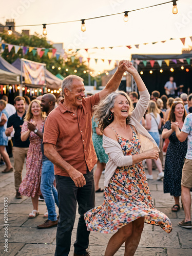 Senior couple dancing at an outdoor summer festival, illustrating active aging and a joyful mature relationship.