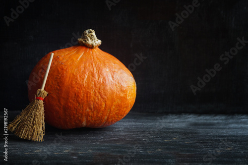 Orange pumpkin with a broom on a black background