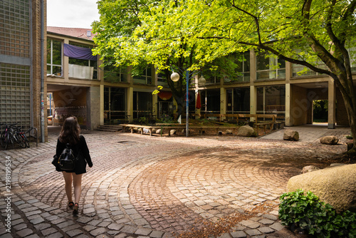 Woman Walking Through Shaded Urban Courtyard