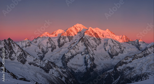 Snow-covered mountain massif glowing pink at alpenglow sunset