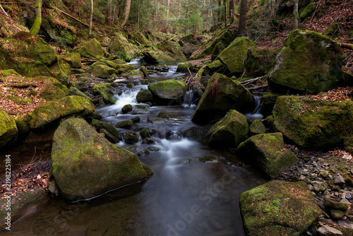 Waterfall on the mountain Carpathian river among mossy boulders, fast flow, crystal water. water flowing between mossy rocks. nature background with river through fores