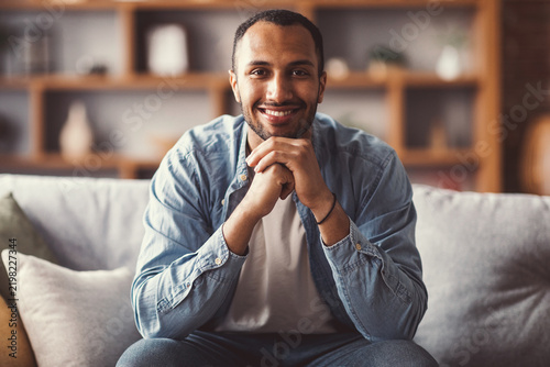 Cuadro en lienzo Happy Smiling Young African American Man Posing Comfortably At Home While Relaxing On Sofa, Showing Joy And Contentment In Cozy Living Room Setting