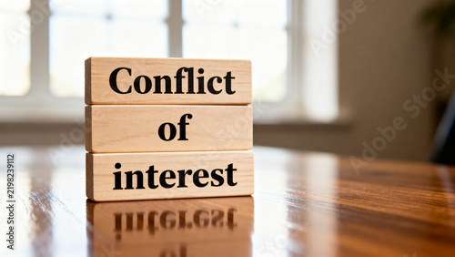 Conflict of interest text on wooden blocks on a reflective table indoors