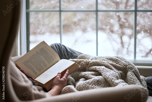 POV Reading Book on Armchair by Window on Snowy Day.
