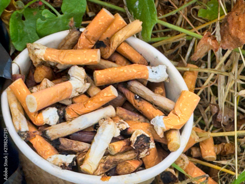 Discarded Cigarette Butts Overflowing from Paper Cup in Nature, Environmental Pollution and Litter Concept