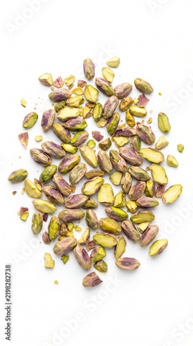 A pile of shelled, bright green pistachio kernels, some with a hint of purple skin, scattered on a clean white background.