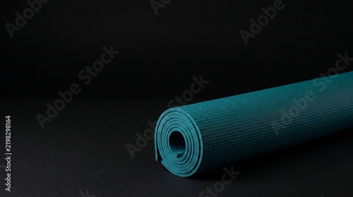 Rolled dark green yoga mat on a black background illustration