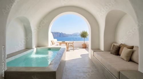 Luxury cave suite with indoor pool overlooking a sunny Mediterranean sea terrace, featuring white arched plaster walls and minimalist decor.