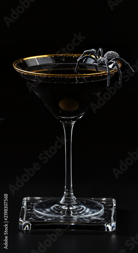 Black cocktail garnished with a spider on a dark background  